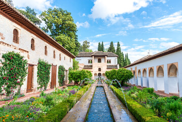 Historic courtyard garden with fountains and traditional Andalusian architecture under a bright blue sky in Granada’s Albayzín district