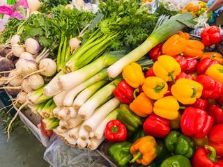 Assortment of vegetables and greens on farmers market stall close up.