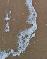 waves foam on the sand