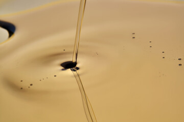 Texture of pouring cosmetic oil on a golden background.