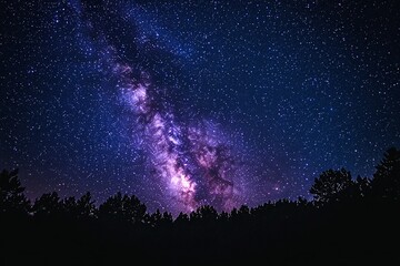 Majestic Milky Way galaxy stretches across a dark night sky, silhouetted by a dense forest. A breathtaking cosmic panorama.