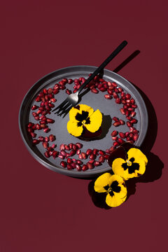 Edible pansy and pomegranate arrangement on maroon theme