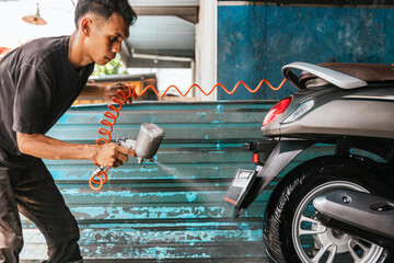 Motorcycle cleaner carefully washing scooter on a workshop