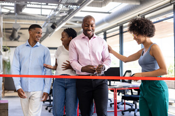 Celebrating office opening, diverse colleagues smiling during ribbon-cutting ceremony