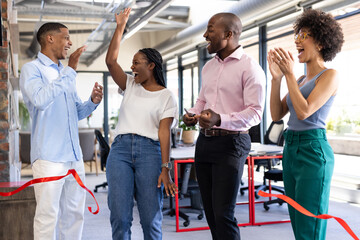 Diverse colleagues celebrating office opening, cutting ribbon and cheering with excitement