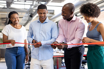 Cutting ribbon at office opening, diverse colleagues smiling and celebrating together