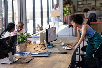 Discussing project with charts on computer, diverse colleagues in office