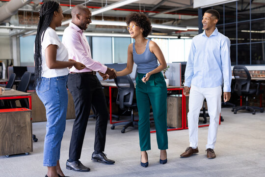 diverse colleagues shaking hands and smiling in modern office environment