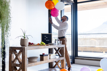 Decorating office with balloons, man arranging colorful decorations for farewell party