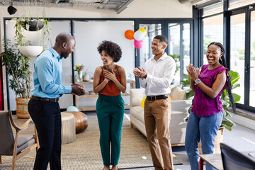 Diverse colleagues celebrating success in modern office, clapping and smiling with joy