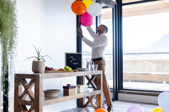 Decorating office with balloons, man arranging colorful decorations for farewell party