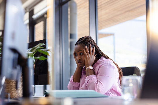 woman in office looking stressed while working on computer