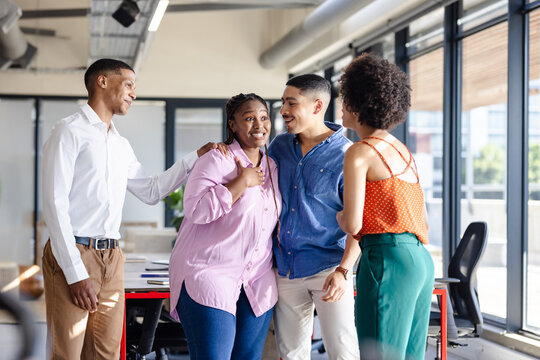 Diverse colleagues in office smiling and chatting during casual diverse team meeting
