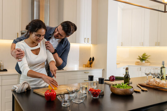 Couple cooking together in modern kitchen, preparing fresh vegetables and smiling, copy space, at ho