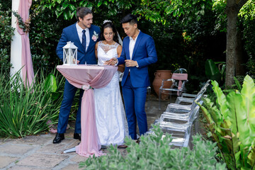 Bride and groomsmen signing wedding documents outdoors in lush garden setting
