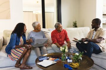 Diverse family discussing home renovation ideas with color swatches and laptop on sofa