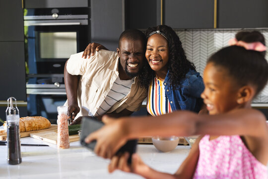 diverse family smiling while taking selfie together in modern kitchen, at home