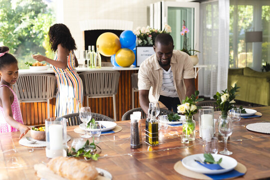 Setting table for in garden celebration, diverse family spending time together, at home