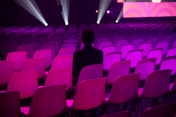 Indian man in a brightly lit empty auditorium at a conference of AI