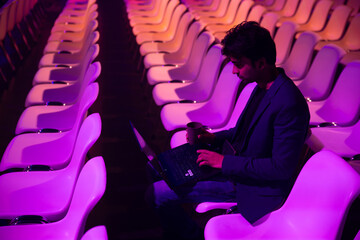 Indian man working with laptop in auditorium at a conference of AI