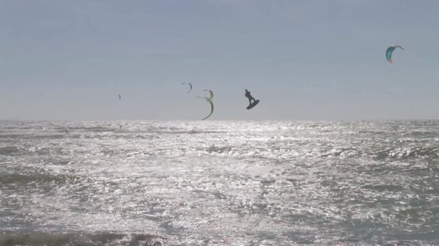Kitesurfers glide over the waves enjoying on a windy day at the Canos de Meca, a wild, scenic beach along Vejer de la Frontera's coast in Cadiz, Andalusia, Spain.