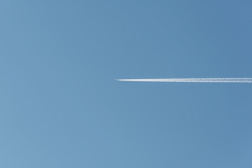 An airplane in a sunny blue sky. The airliner leaves a strong jet trail