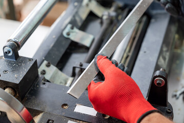 A woodworker in gloves with new sharp knife. Professional carpenter installing a new knife in a...