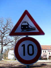 Warnschild an einem unbeschrankten Bahnübergang mit Schild Höchstgeschwindigkeit