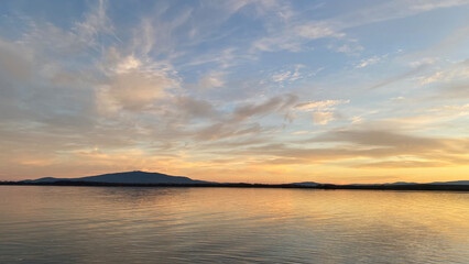 Tranquil evening at a European lake with a dramatic sunset sky. Gentle waves, vibrant reflections,...