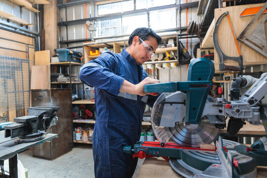 Woodworker operating an electric saw, cutting wooden planks with precision in his carpentry workshop - Powered by Adobe