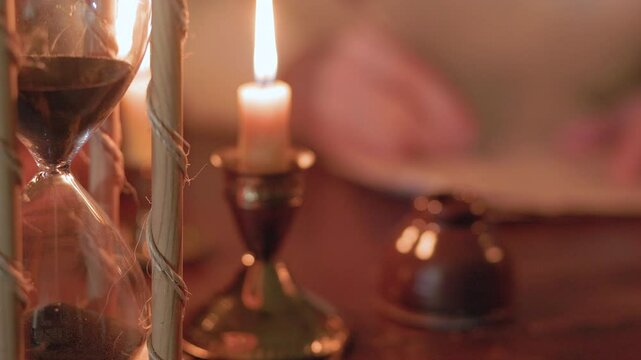 18th century man writing at his desk focus on hourglass