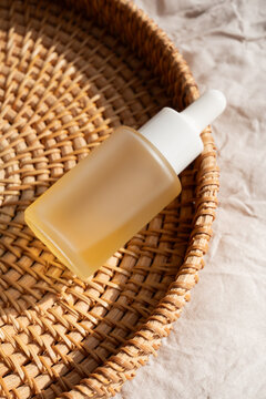 Essential oil dropper bottle on woven basket with soft lighting