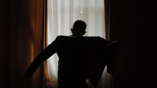Businessman putting on jacket near window
