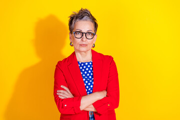 Confident Middle-Aged Woman in Stylish Red Blazer Posing Against Bright Yellow Background with...