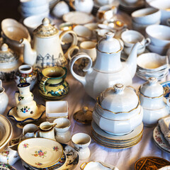 Assortment of vintage porcelain tableware with gold trim at a flea market