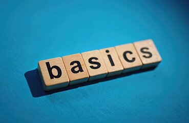 Word basics composed of wooden blocks against vivid blue background. Conceptual symbol for basic knowledge. Copy space for text. Education, beginning, core concept for business and learning.