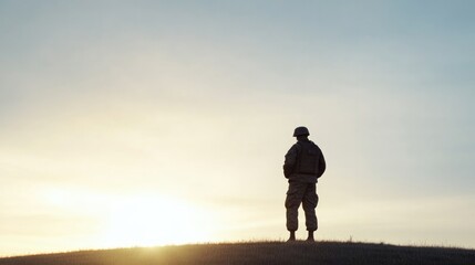 solitary soldier silhouetted against vast open sky during golden hour standing tall on grassy hill capturing essence