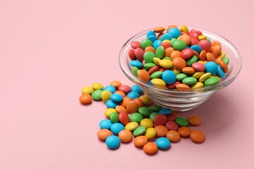 Tasty candies in bowl on pink background, closeup. Space for text