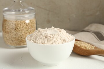Brown rice and flour on white table, closeup