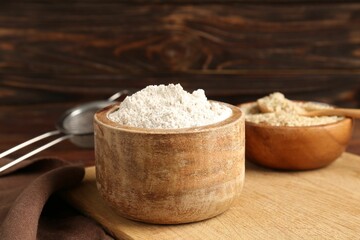 Brown rice, flour and sieve on wooden table, closeup