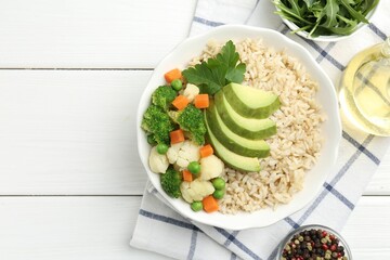 Tasty brown rice with vegetables and products on white wooden table, flat lay. Space for text
