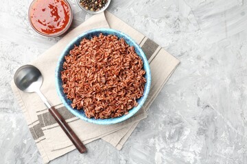Delicious brown rice served on grey textured table, flat lay. Space for text