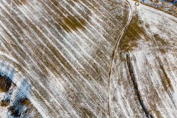 Agricultural field in winter with quad bike tracks, abstract view from high altitude