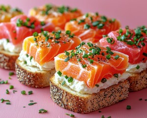 Colorful salmon and tuna tartines garnished with chives on a pink background