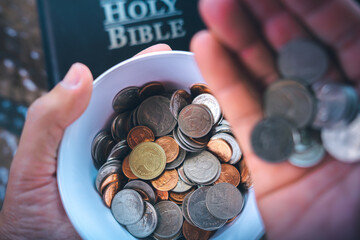 Coins with Holy Bible, a closeup, Christian biblical concept of tithing, Biblical concept of...