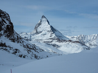 Matterhorn mountain in winter with snow-covered slopes and clear blue sky.