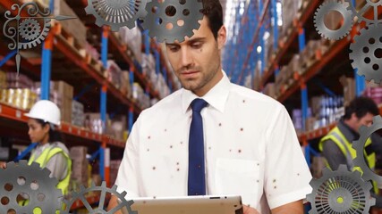 In warehouse, worker using tablet with animation of gears overlaying scene - Powered by Adobe