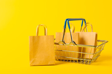 Online shopping concept.Cardboard box and shopping bags in a trolley on a bright colored...