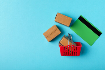 Online shopping concept.Cardboard box and shopping bags in a trolley on a bright colored background. Shopping basket. Online shopping using a laptop, tablet, phone and credit card. Home delivery.