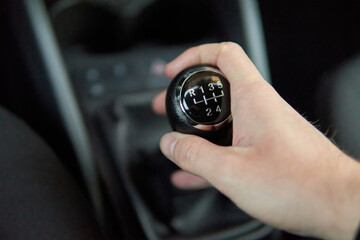 Man holding Manual gearbox transmission gear shifter knob handle stick shift in the car interior
